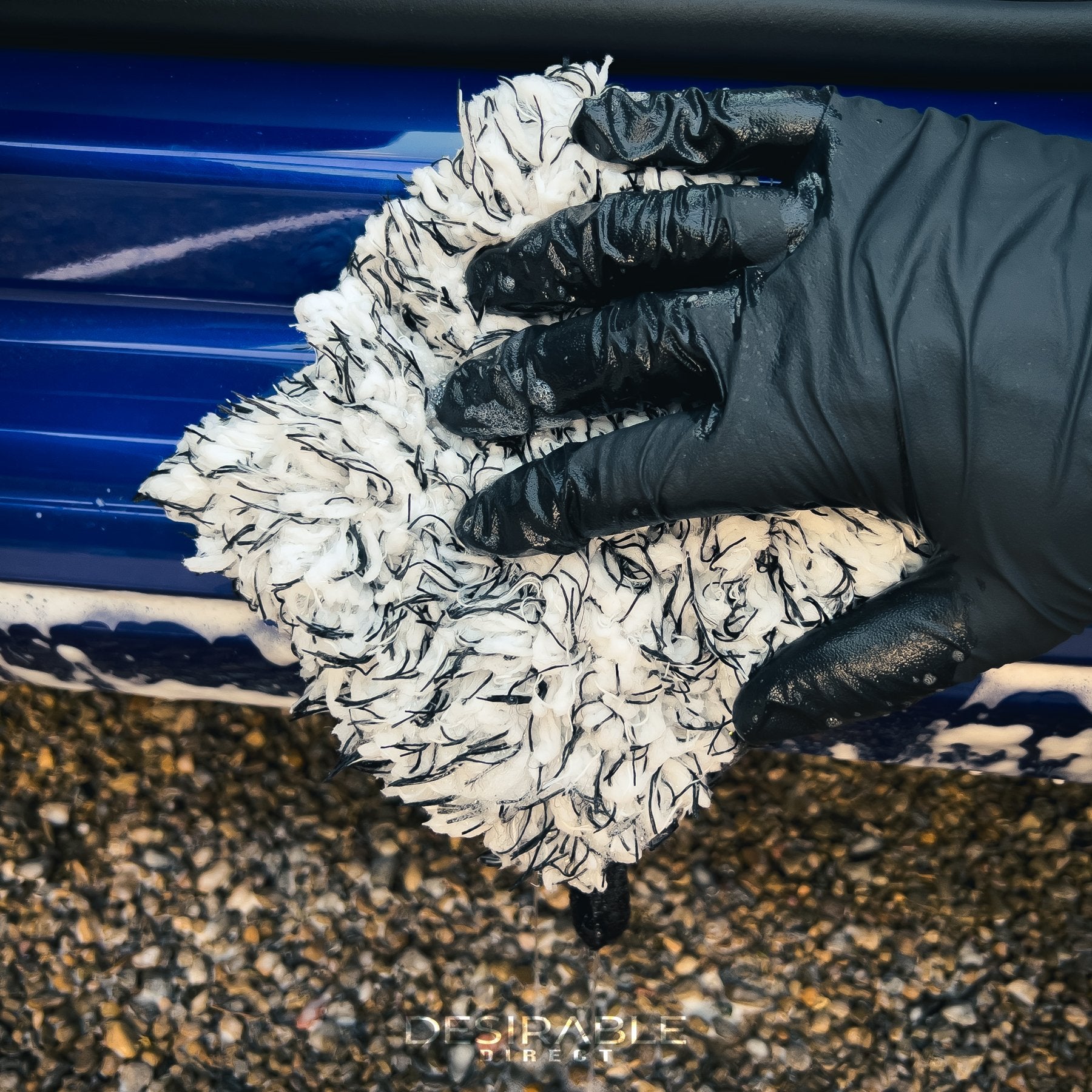 Car care microfibre black and white wheel and trim wash mitt cleaning the passenger side door trim on a blue volkswagen golf r.