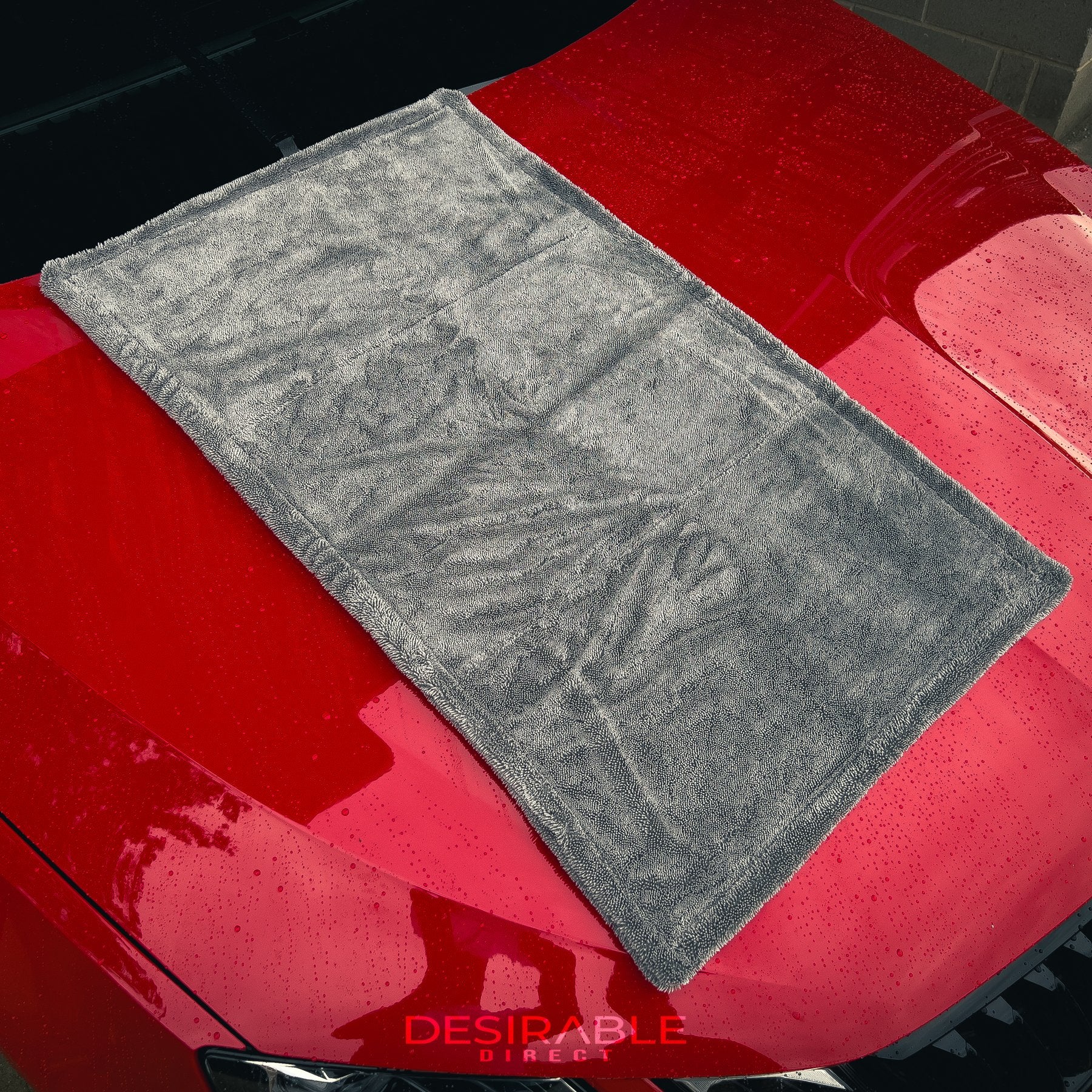 Car care large twisted pile grey drying towel displayed on the bonnet of a red car. The vehicle is wet to showcase the drying capability of the towel.