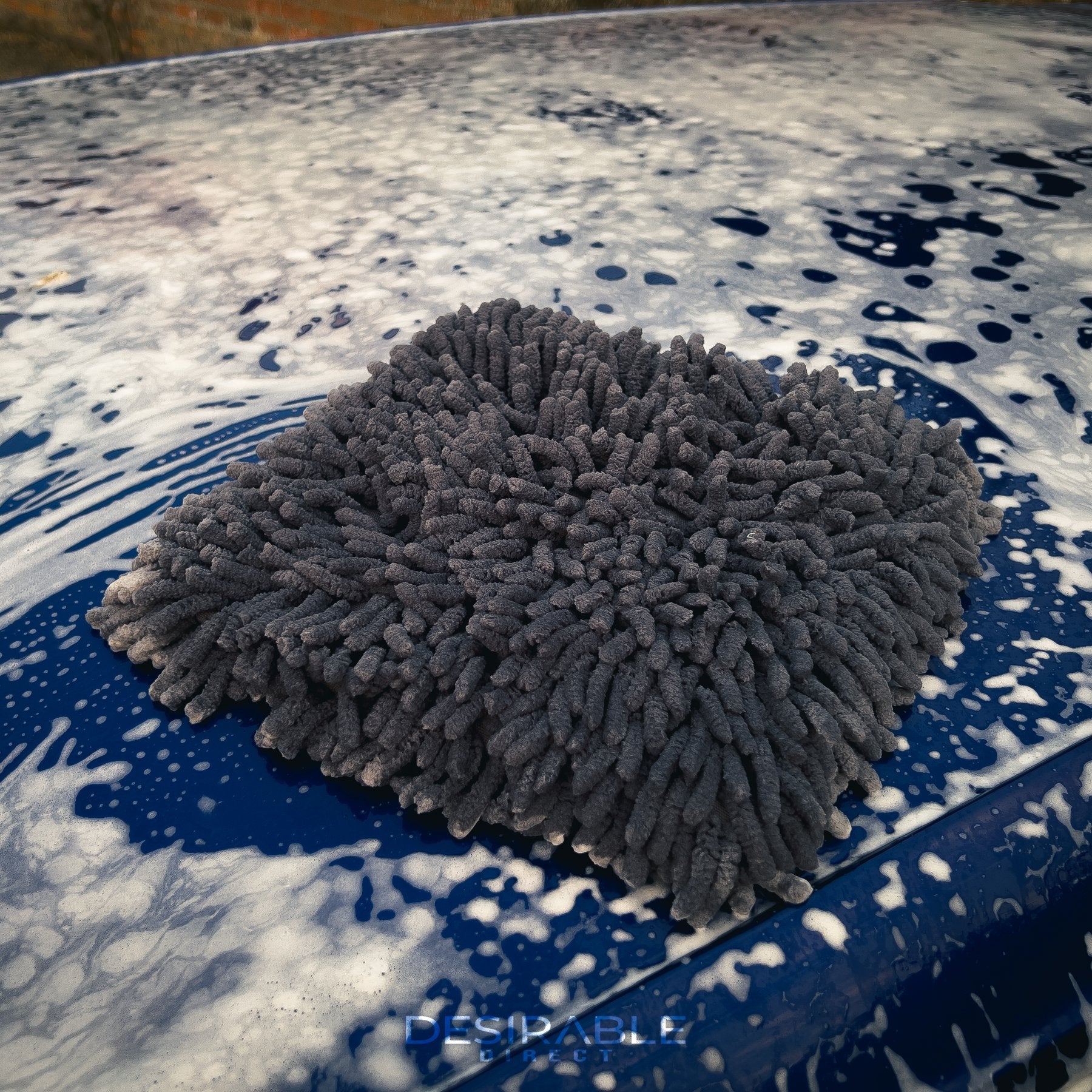Car care large grey noodle wash pad. The wash pad is covered in car shampoo, on the roof of a blue volkswagen golf r which is also covered in car shampoo.