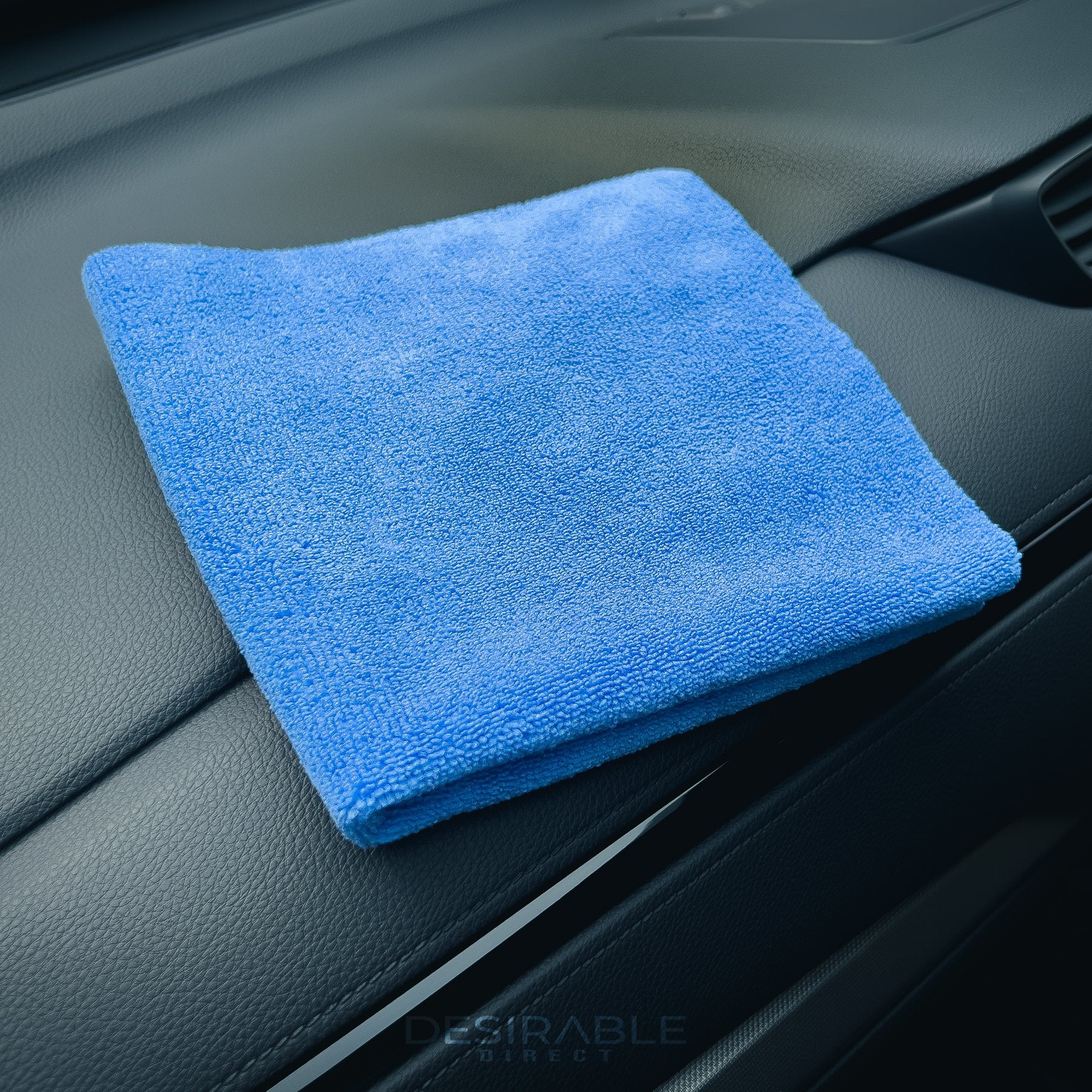 Car care microfibre soft blue multi-purpose cloth 40x40cm folded on the dashboard of a grey car.