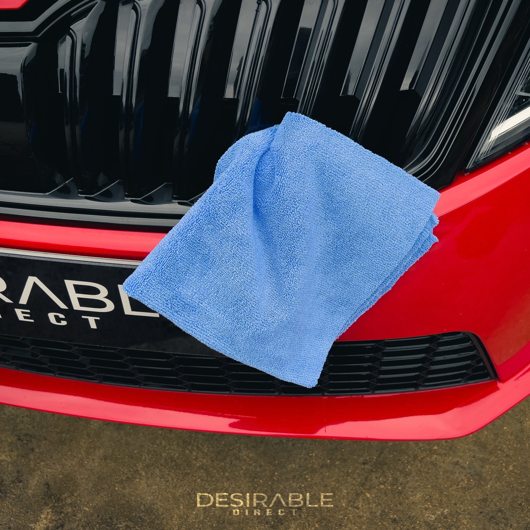 Car care microfibre soft blue multi-purpose cloth 40x40cm in the grill at the front of a red car.