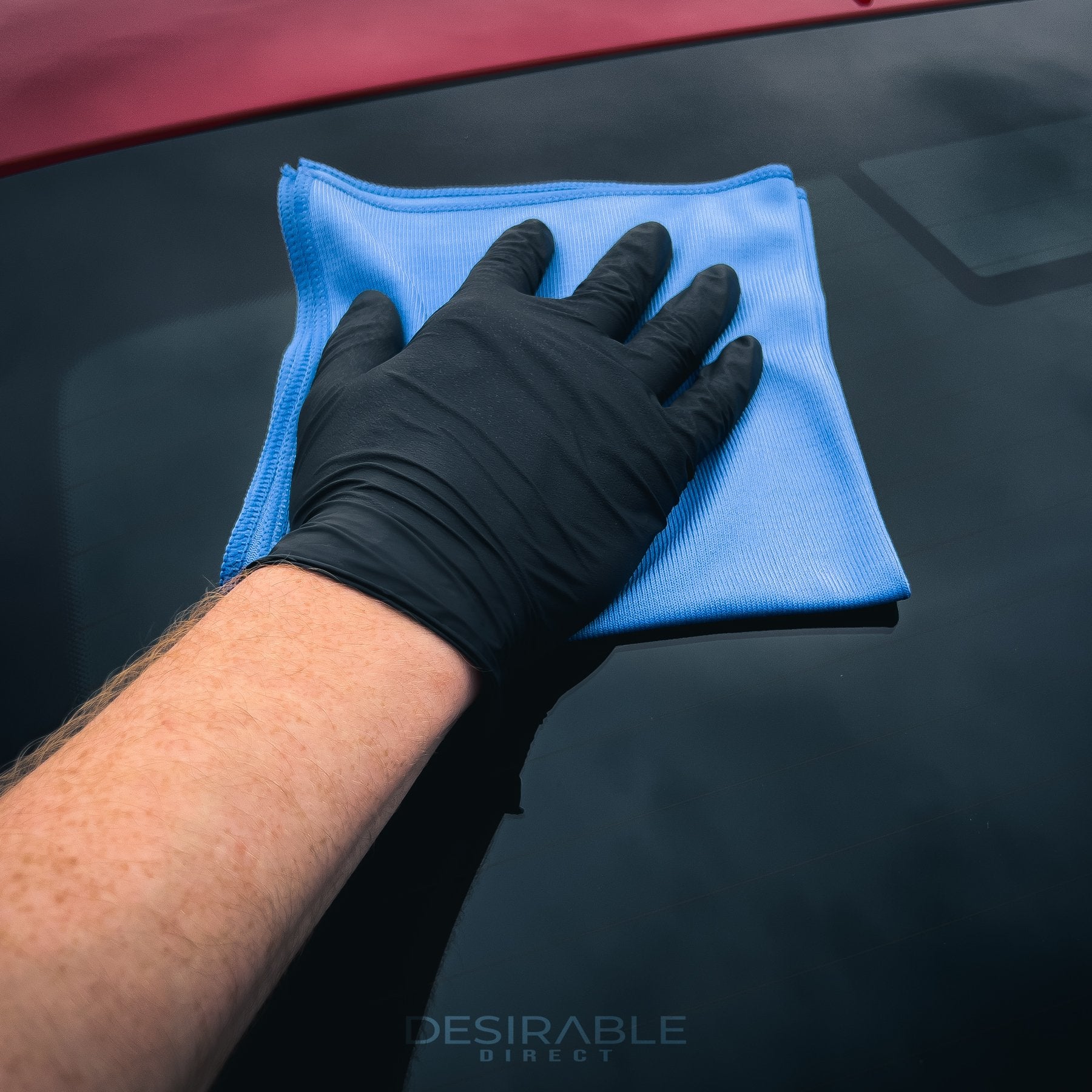 Car care microfibre blue glass cloth 40x40cm cleaning the windscreen of a red car.