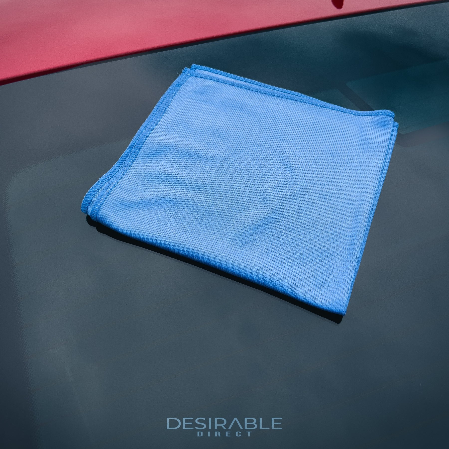 Car care microfibre blue glass cloth 40x40cm displayed on the windscreen of a red car.