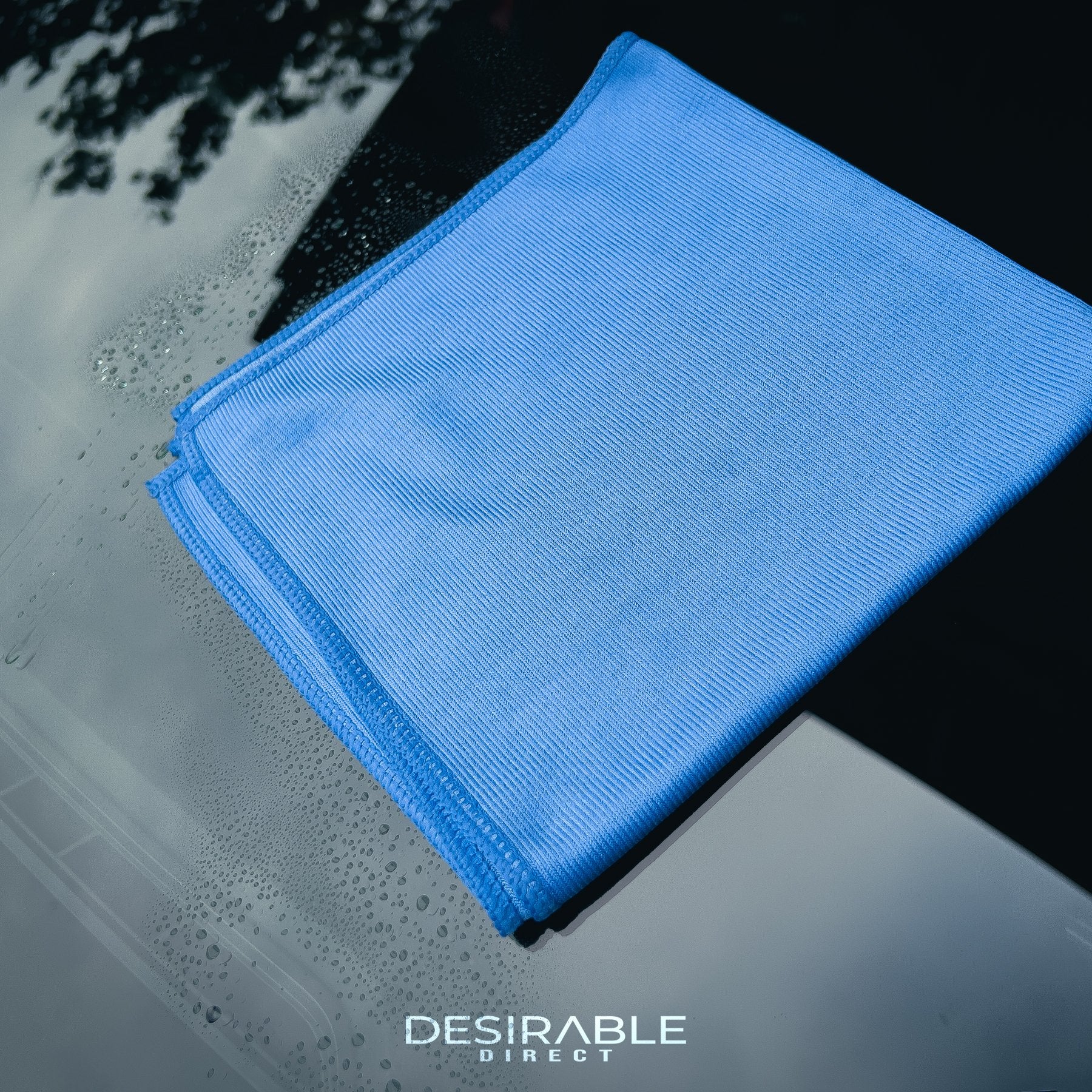 Car care microfibre blue glass cloth 40x40cm displayed on a car windscreen with car glass cleaner on the glass.