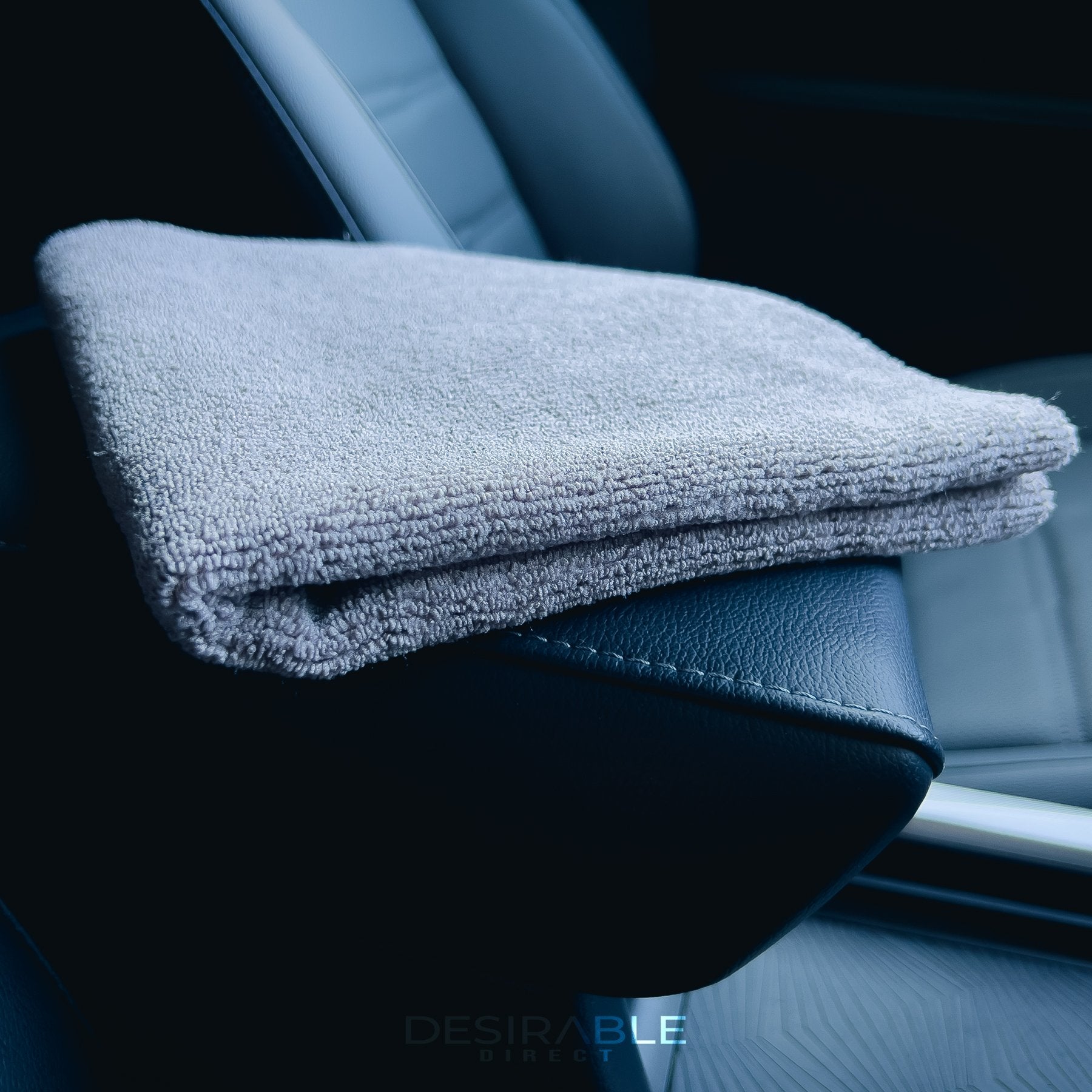 Car care microfibre grey cloth 40x40cm folded on a leather armrest in a car.