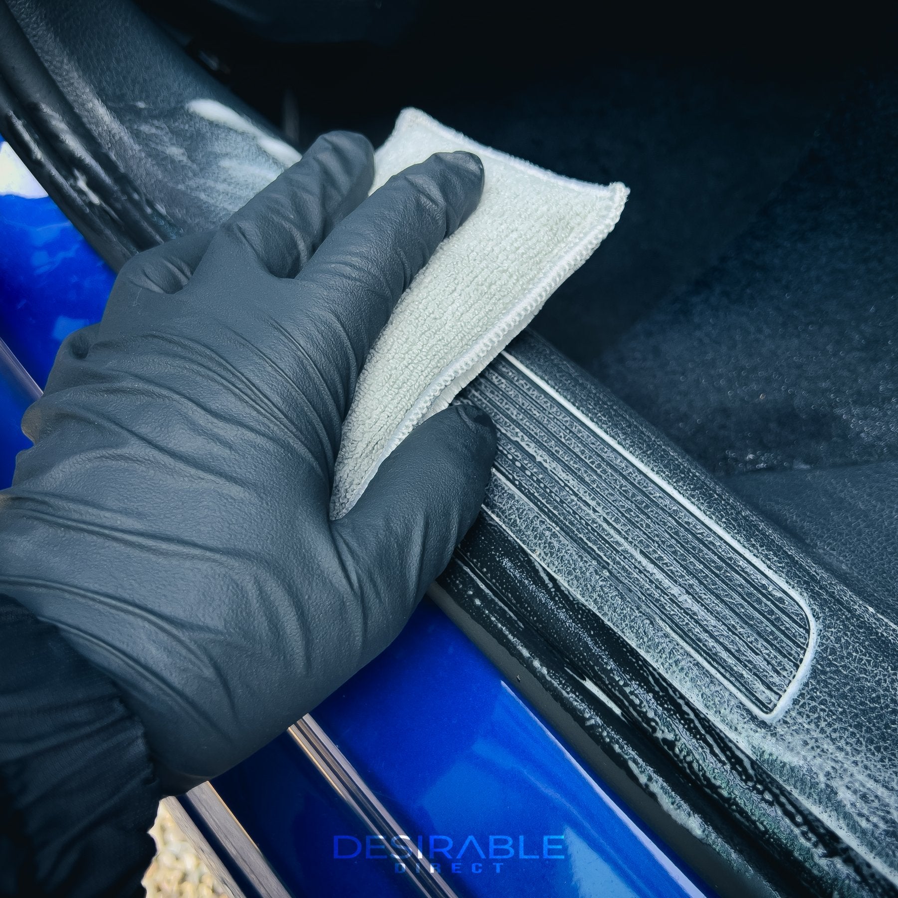 Car care one microfibre grey interior scrub pad cleaning the passenger side door trim of a blue volkswagen golf r.