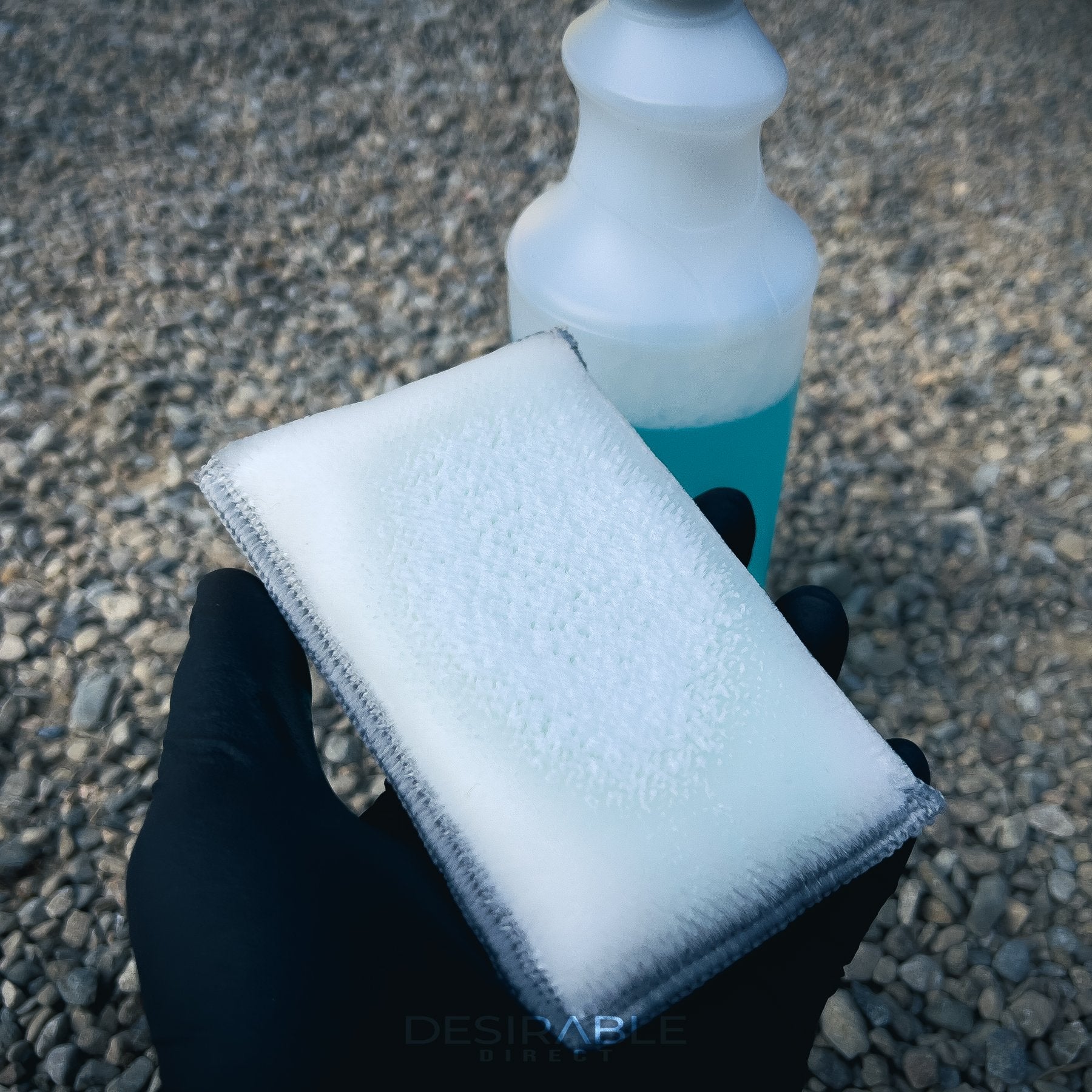 Car care one microfibre grey interior scrub pad showing the side with bristles. Somebody is holding the pad and wearing black gloves.