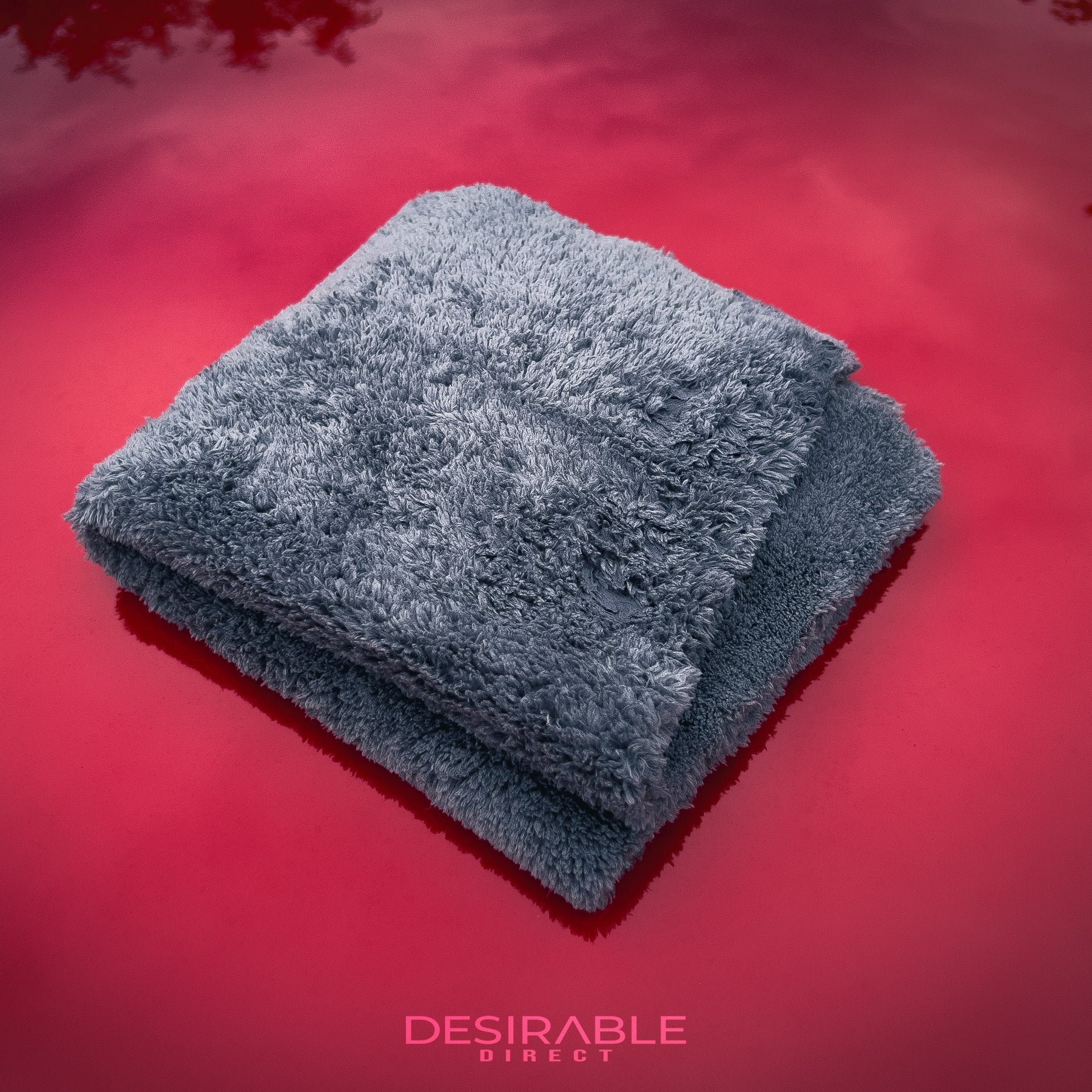 Car care plush grey microfibre cloth folded and displayed on the bonnet of a red car.