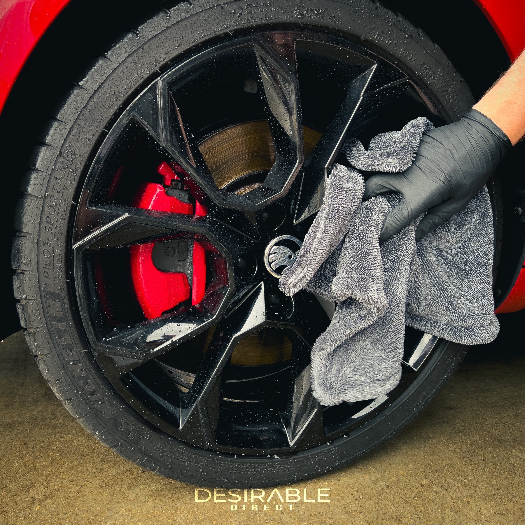 Car care small twisted pile grey microfibre wheel and trim 40x40cm drying towel drying a black alloy on a red car. This is from another angle to show the towel.