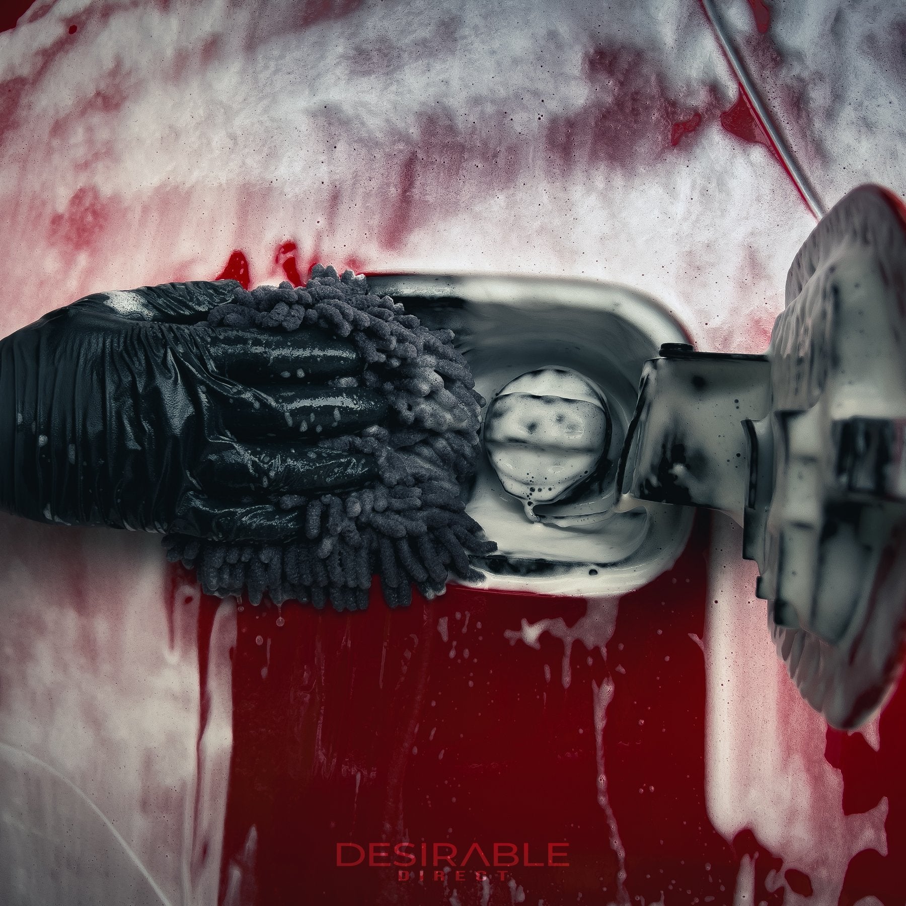 Car care chenille grey wheel and trim noodle wash pad cleaning the fuel filler cap of a red car covered in car shampoo.