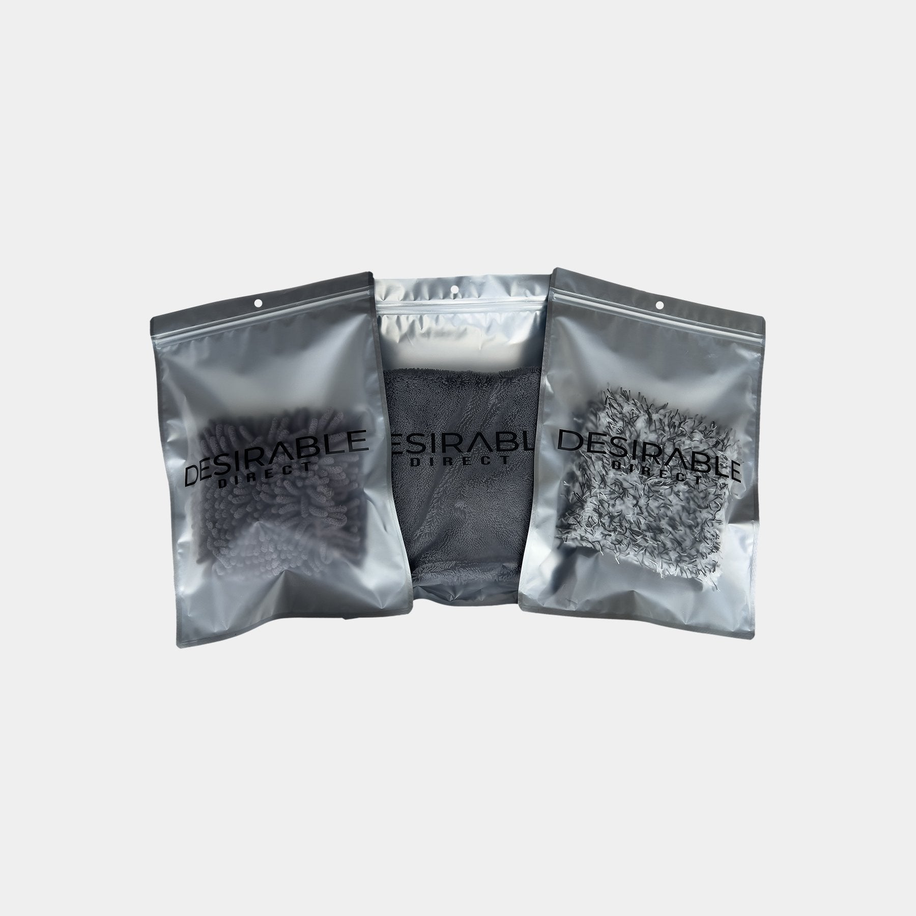 Car care microfibre wheel cleaning wash and dry bundle displayed on a white background in silver packaging with desirable direct printed on the front to keep the item clean when not in use. A small drying towel, wheel mitt and wash pad.