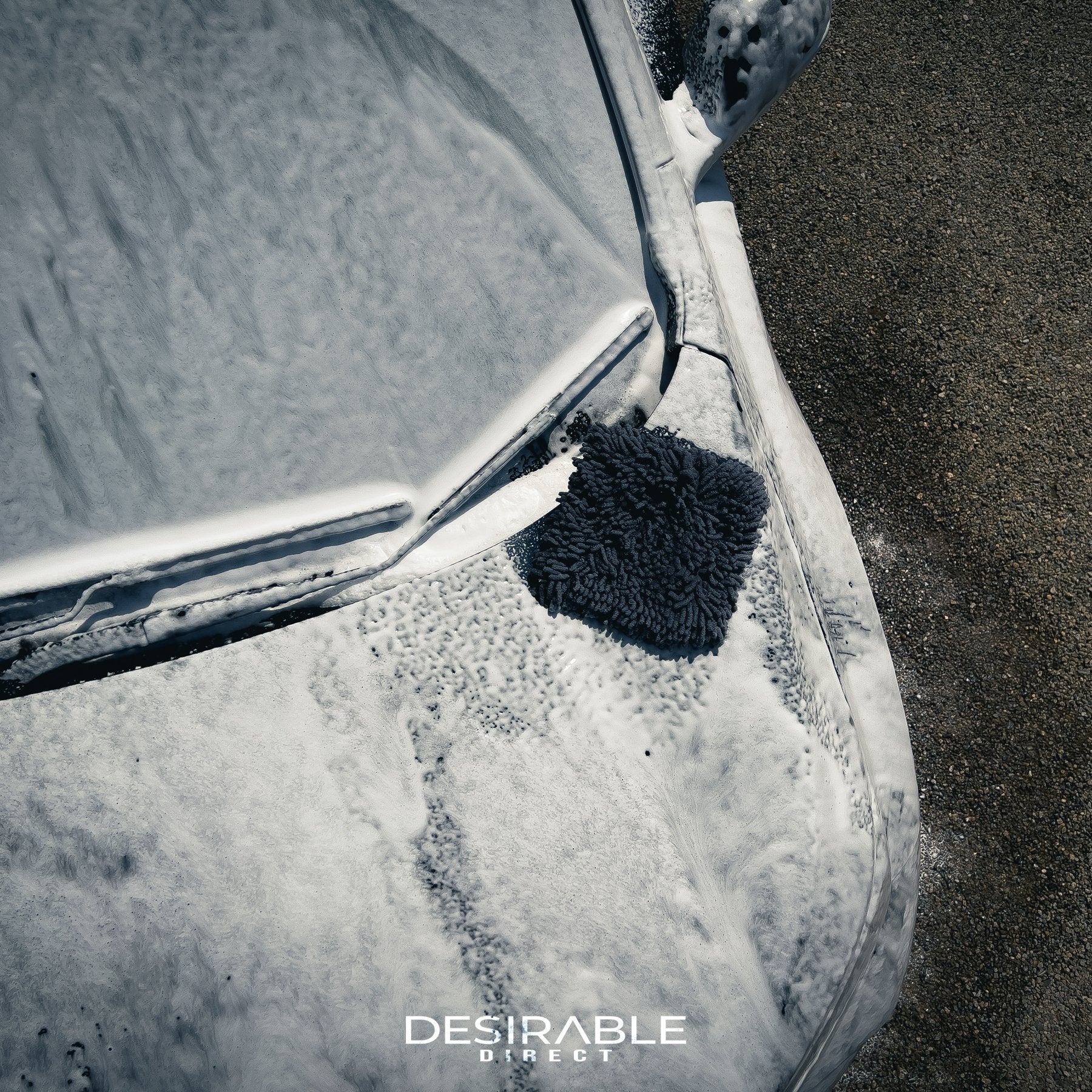 Car care noodle grey large pad on the bonnet of a grey car covered in car shampoo. The photo is taken from an aerial shot to show the wash pad.