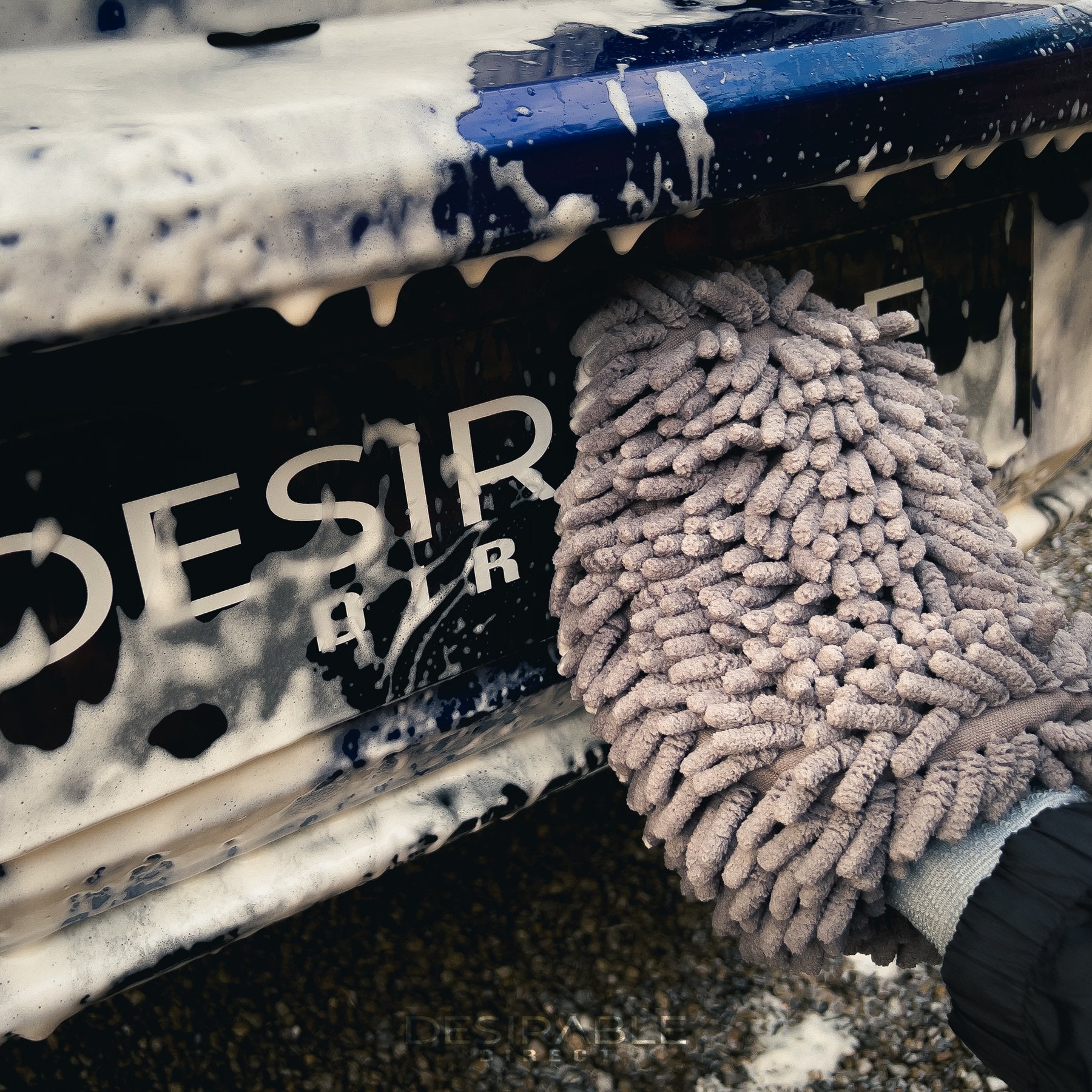 Car care noodle grey wash mitt cleaning the back of a blue volkswagen golf r